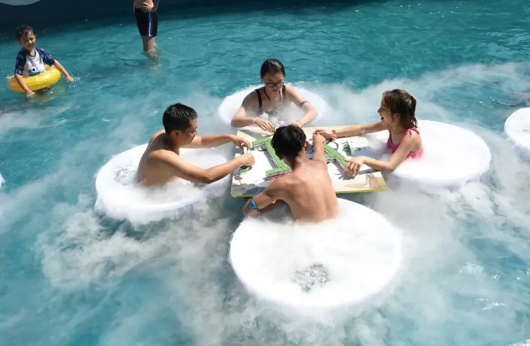 重庆的水上乐园内,工作人员把干冰和冰块倒入水桶,让游客在冰凉的水中打麻将。(图 / 陈超 中新社)