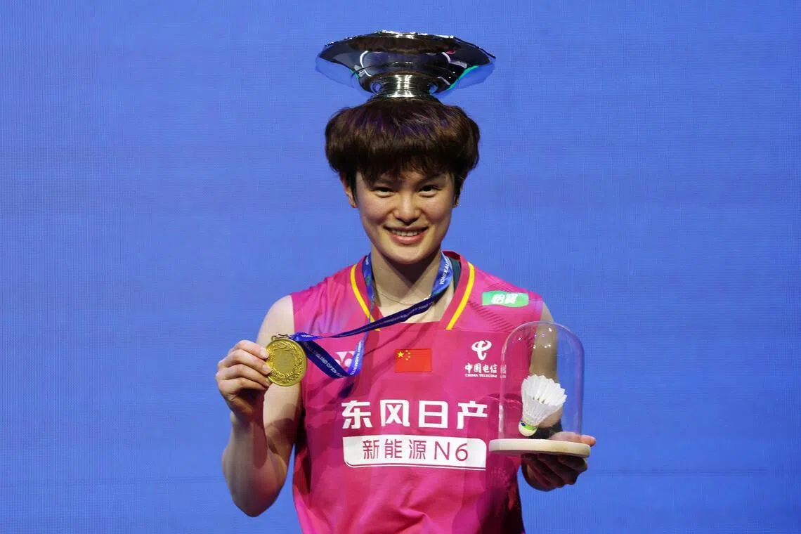 王祉怡把冠军奖座放在头顶上，手持奖牌和纪念品合影。（路透社）