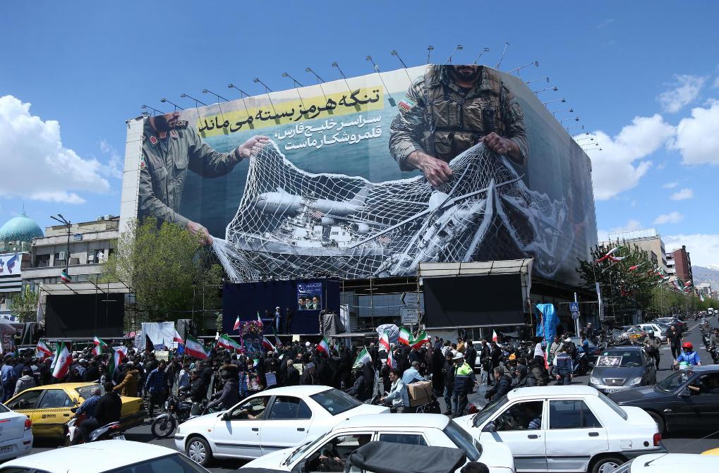 4月8日,民众在伊朗首都德黑兰革命广场参加集会。广场的大幅宣传画上描绘着伊朗武装人员的形象,文字内容是“霍尔木兹海峡仍然关闭 整个波斯湾都是我们的猎场”。