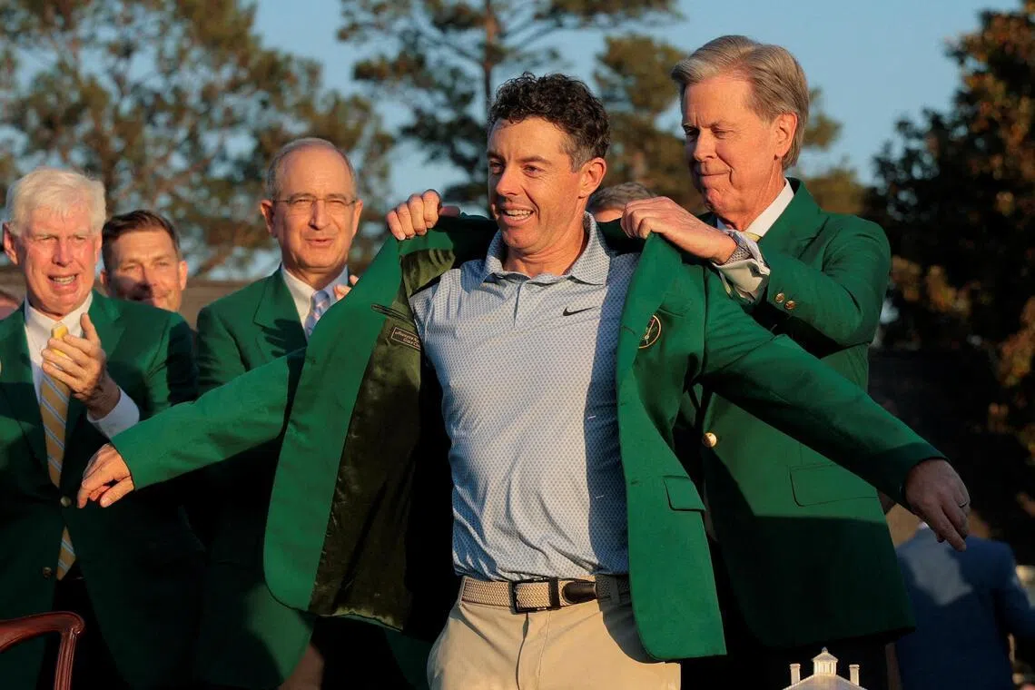 弗雷德·里德利（右）为麦克罗伊披上象征冠军的绿夹克。（路透社）