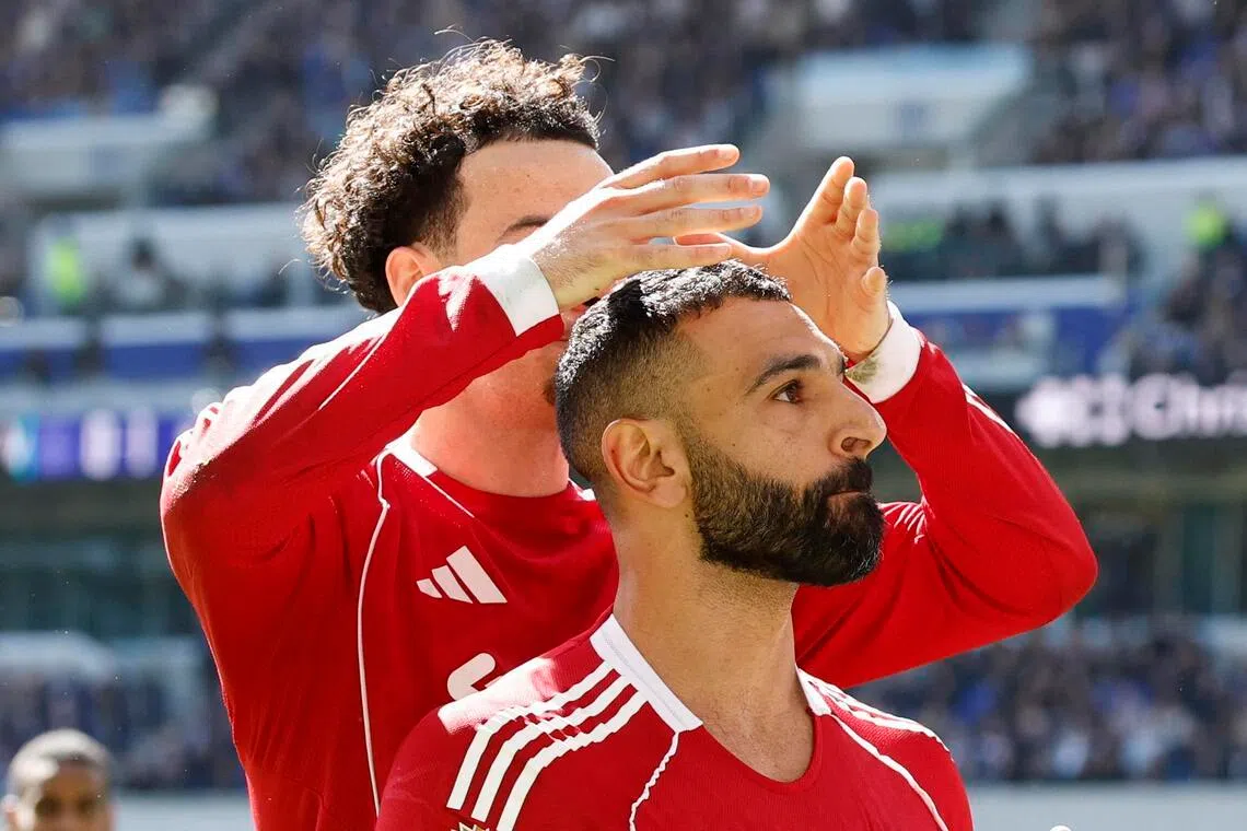 萨拉赫（前）进球、达成个人里程碑后，队友琼斯为他“戴上王冠”。（路透社）