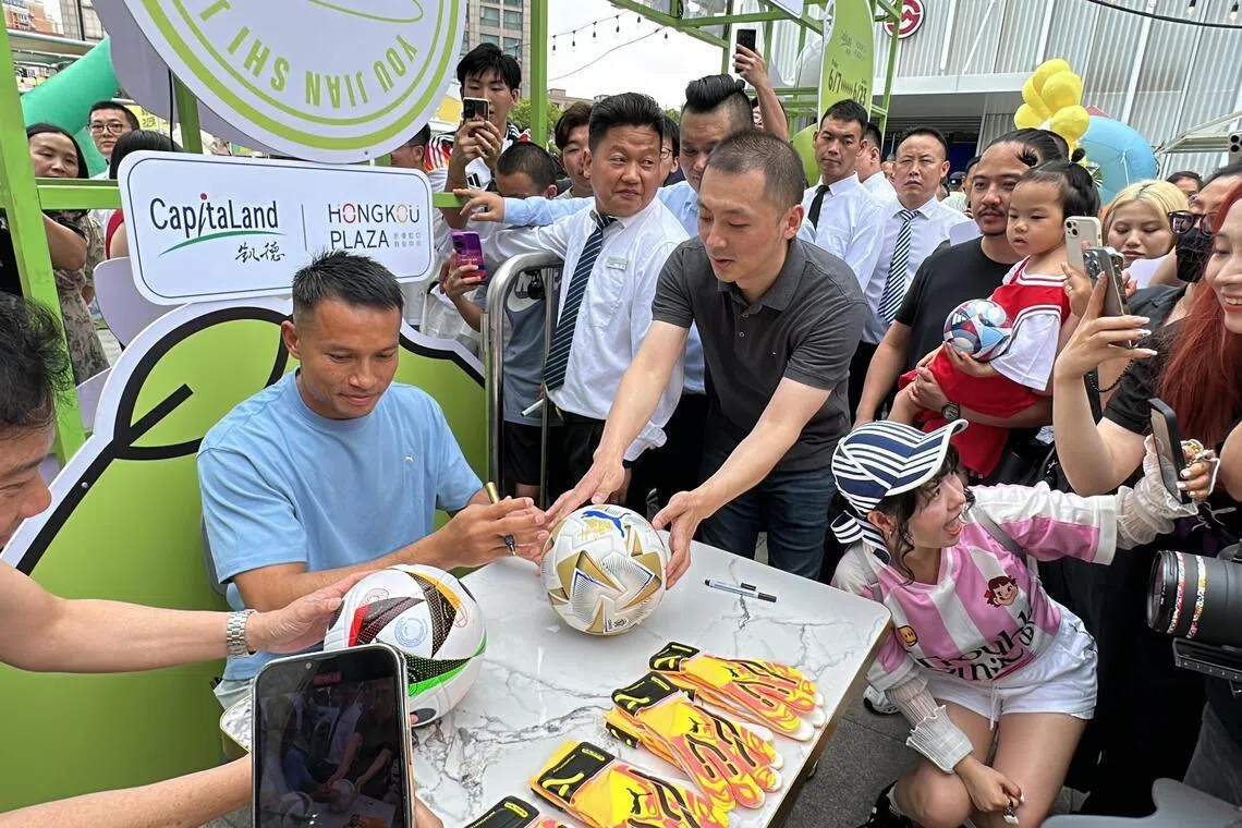 间接帮助中国晋级后，时任雄狮门将哈山（蓝衣）受邀前往上海参加商业活动，并在为球迷签名、制作椰浆饭，不少民众都前往现场“追星”。（档案照片）